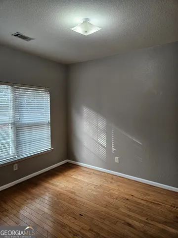 an empty room with wooden floor and windows