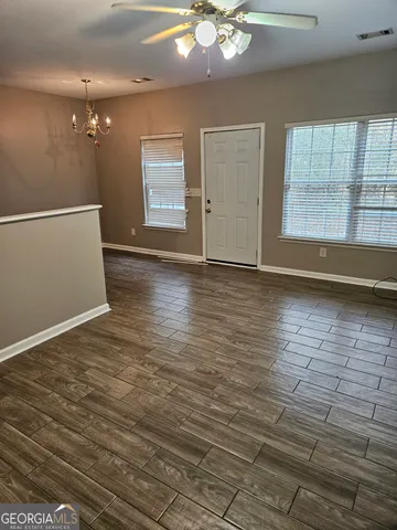 an empty room with wooden floor chandelier and windows