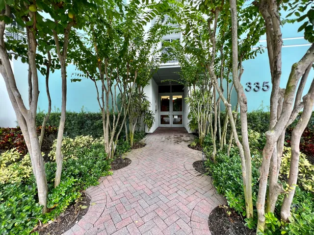 a front view of multi story residential apartment building with yard and green space