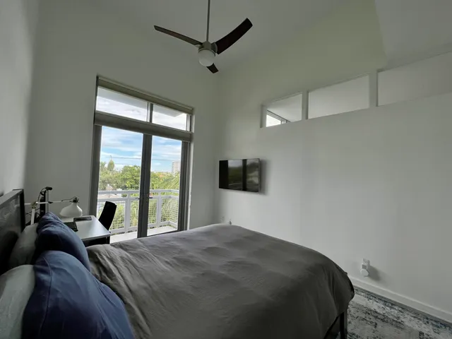 a bed room with a bed a television and a large window