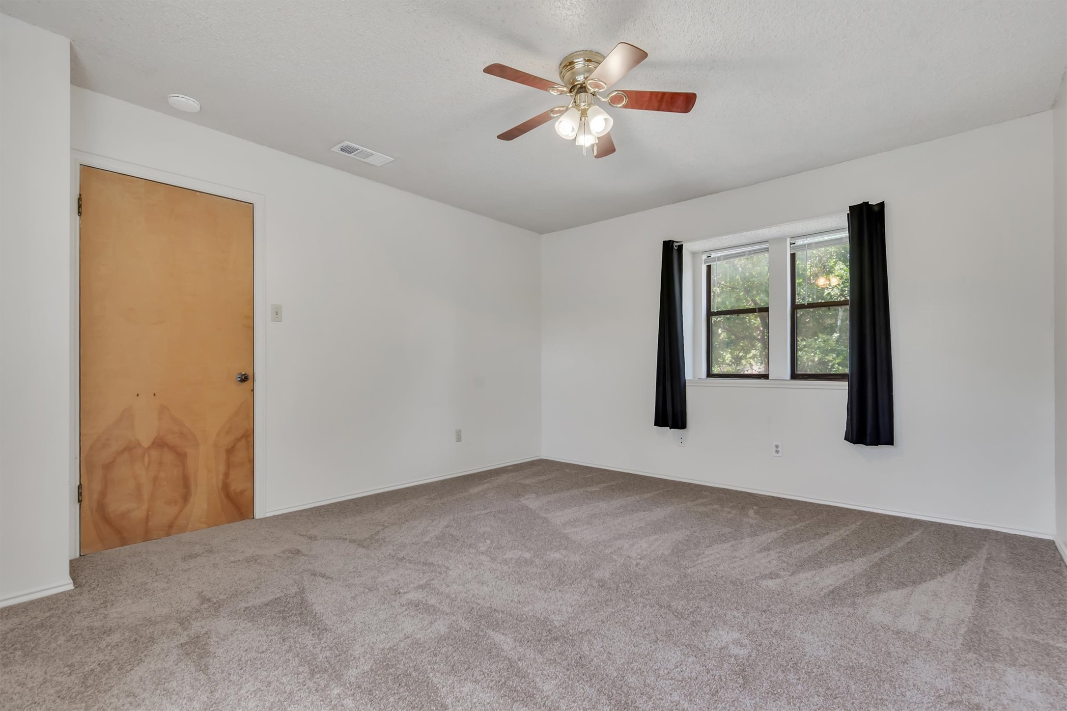 7802 Topawa Cove, Unit B Austin, TX 78729 - Photo 19 of 32 Well-lit bedroom with new carpet and a ceiling fan.
