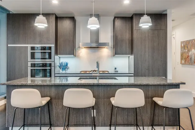 a kitchen with stainless steel appliances granite countertop a table chairs in it and wooden floors