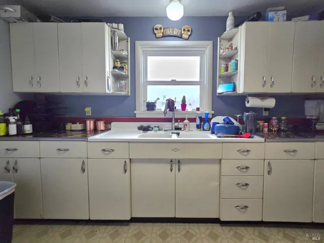 a kitchen that has a lot of cabinets a sink and appliances in it
