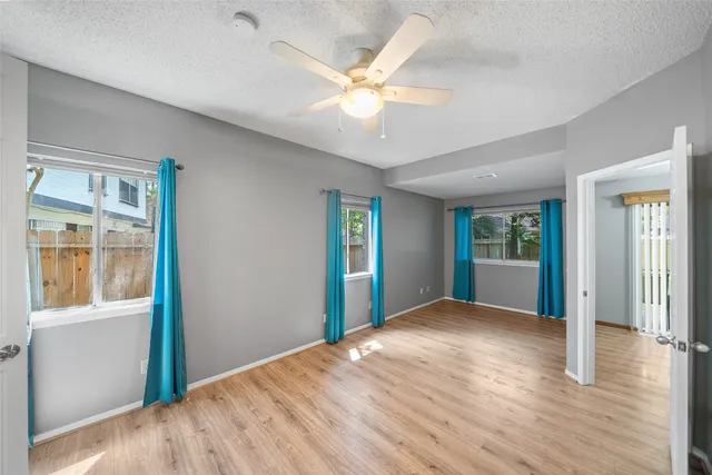 a view of an empty room with window and wooden floor