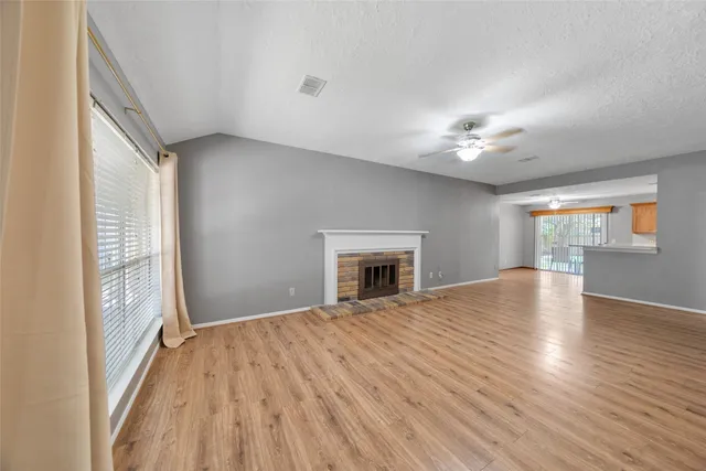 a view of empty room with a fireplace and wooden floor
