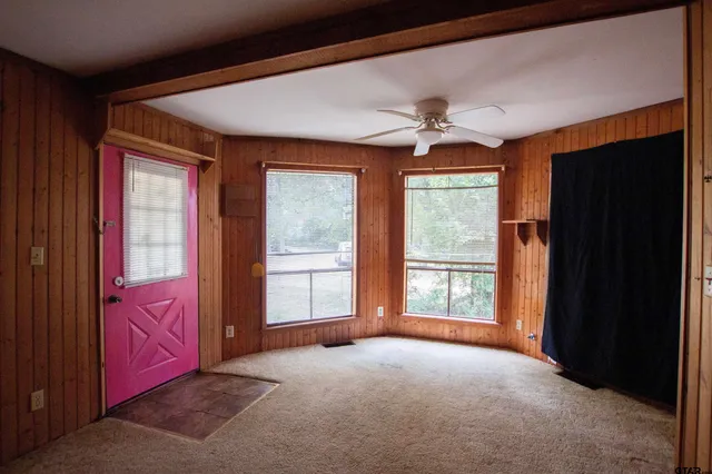 a furnished livingroom with windows and chandelier fan