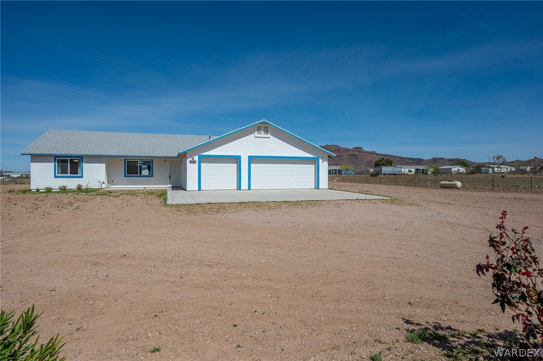3411 West Carmichael Road Golden Valley, AZ 86413 - Photo 74 of 97 View of front of home featuring dirt driveway, an attached garage, and stucco siding