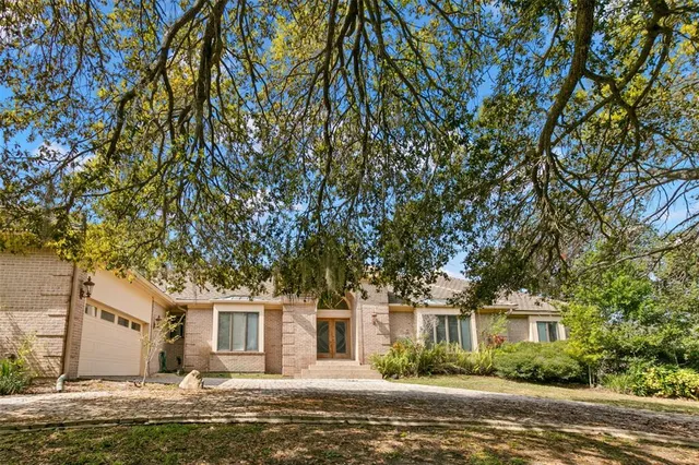 a front view of a house with a garden and tree