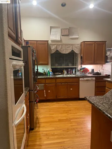 a kitchen with stainless steel appliances granite countertop a sink a stove and a refrigerator