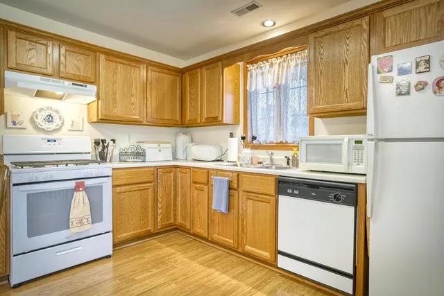 a kitchen with stainless steel appliances granite countertop a stove a sink and white cabinets with wooden floor