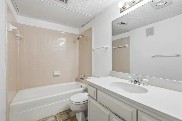 a bathroom with a bathtub shower sink vanity mirror and toilet