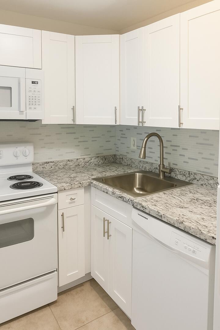 4850 Northeast 5th Avenue, Unit 110 Boca Raton, FL 33431 - Photo 2 of 13 a kitchen with granite countertop white cabinets and white appliances