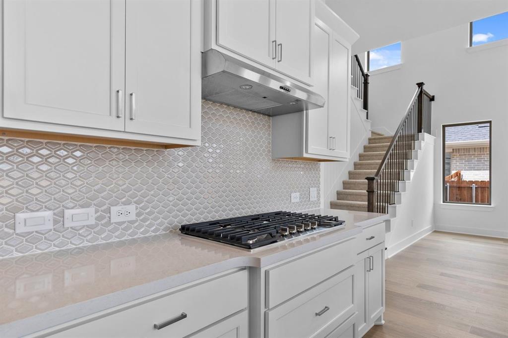 1124 Hitching Post Way Oak Point, TX 75068 - Photo 12 of 34 a kitchen with a stove and white cabinets