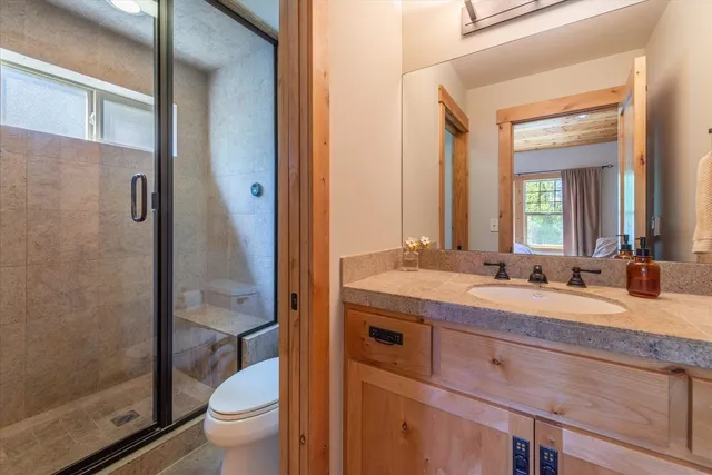 a bathroom with a granite countertop sink a toilet and a mirror
