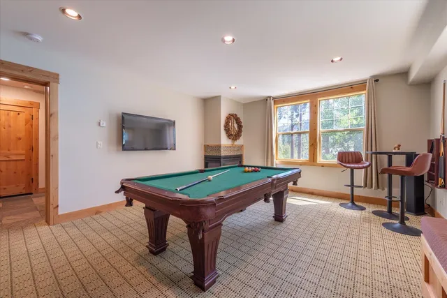 a room with furniture pool table wooden floor and windows