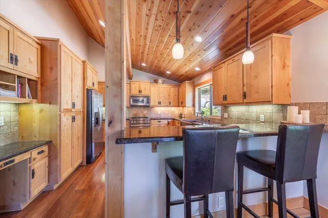 a kitchen with stainless steel appliances granite countertop a table chairs and a refrigerator