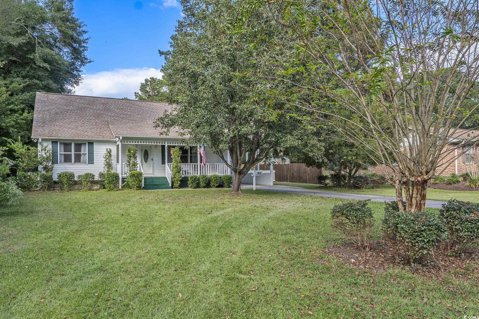 View of front of house with covered porch, a shingled roof, and a front yard