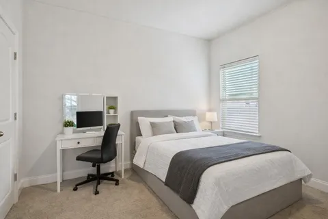 a bedroom with a workspace and a window