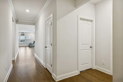a view of a hallway with wooden floor and a bathroom