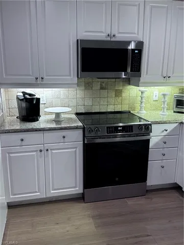 a kitchen with stainless steel appliances granite countertop a stove a microwave and cabinets