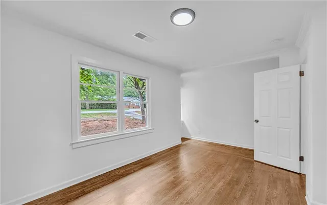 a view of an empty room with wooden floor and a window