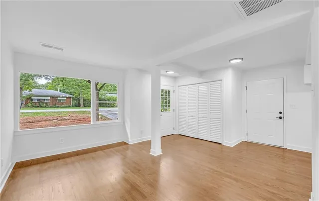 an empty room with wooden floor and windows