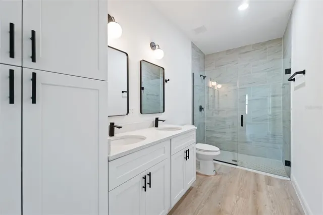 a bathroom with a double vanity sink toilet mirror and shower