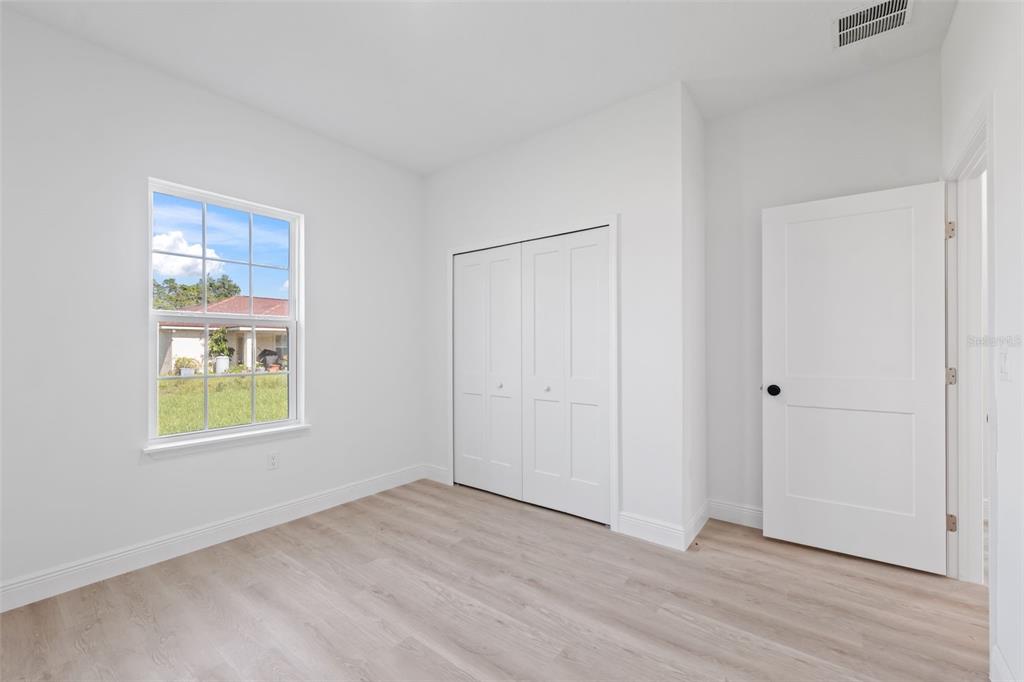 3479 Southwest 137th Loop Ocala, FL 34473 - Photo 21 of 32 a view of an empty room with wooden floor and a window