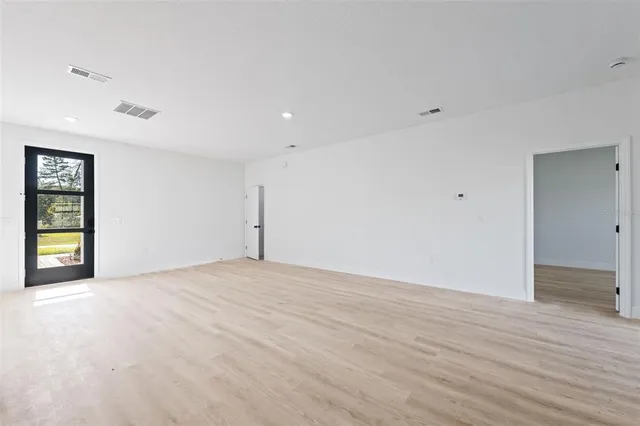 a view of an empty room with wooden floor and window