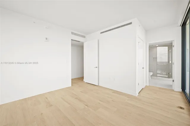 a view of an empty room with wooden floor and glass door