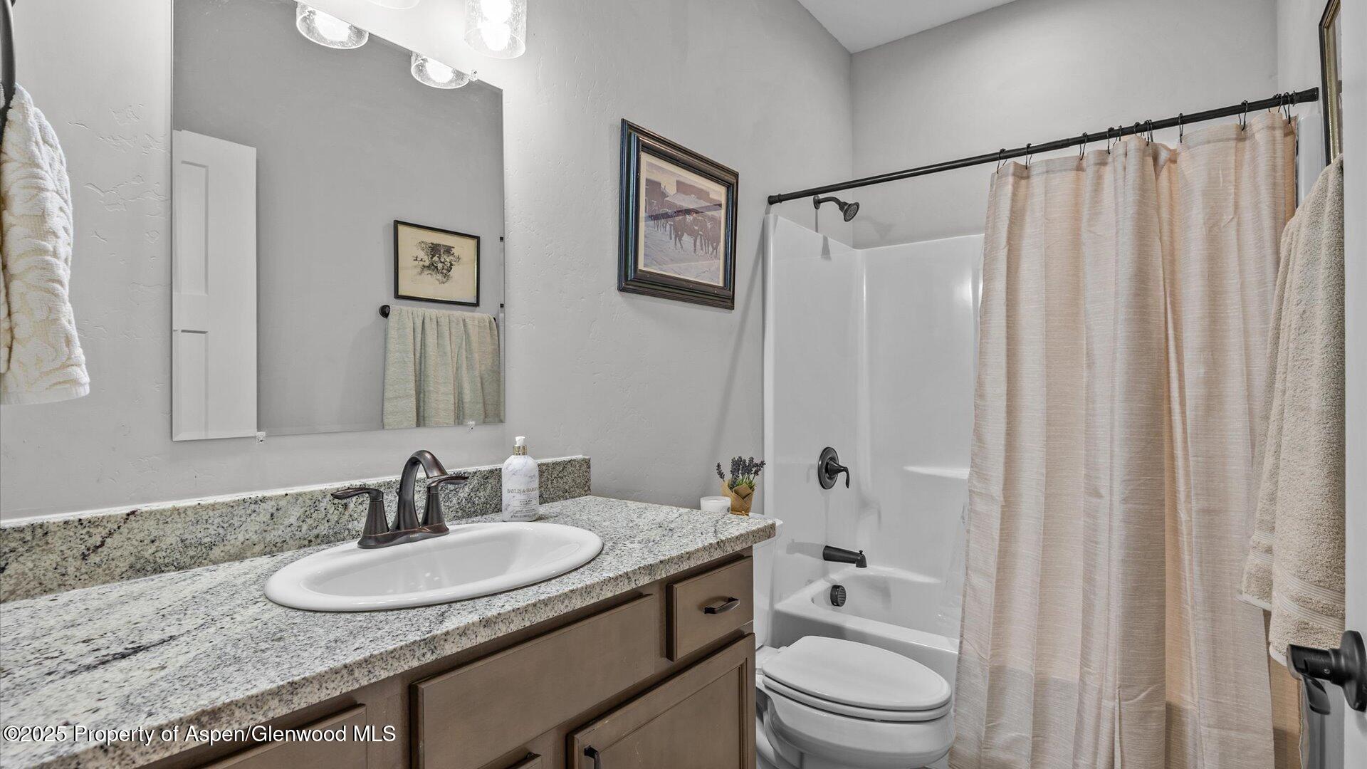 137 Willow Circle Rifle, CO 81650 - Photo 16 of 25 a bathroom with a granite countertop sink toilet a mirror a vanity and shower