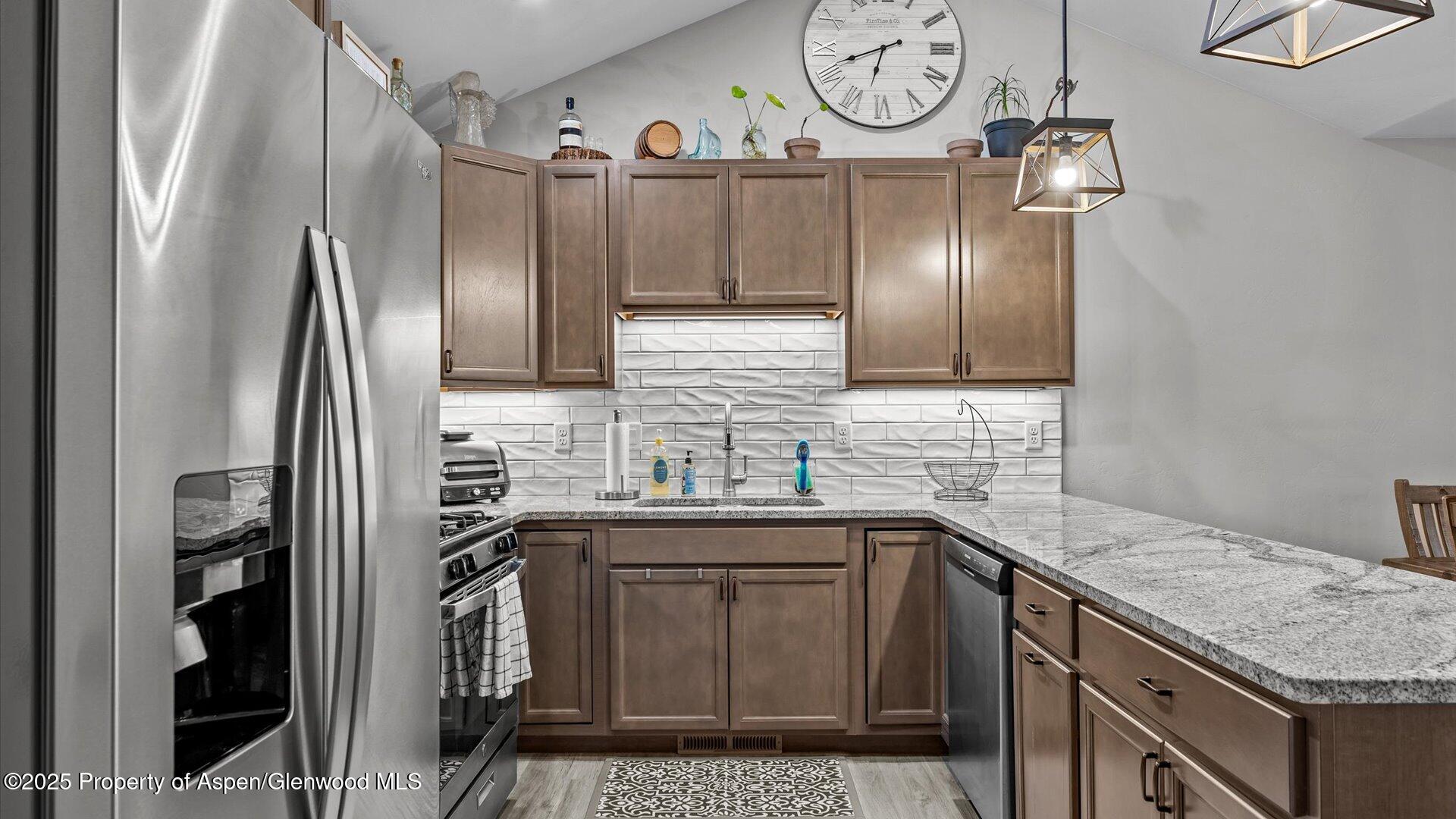 137 Willow Circle Rifle, CO 81650 - Photo 8 of 25 a kitchen with stainless steel appliances granite countertop a sink a stove a refrigerator and a refrigerator with wooden floor