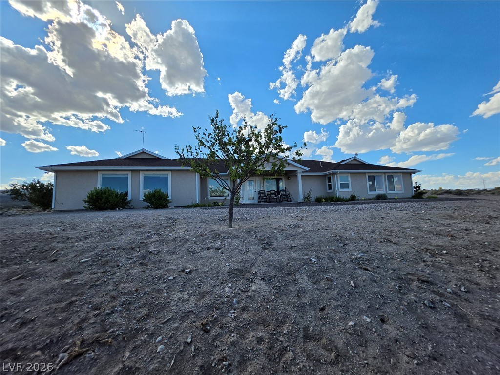 5272 Truman Lane Caliente, NV 89008 - Photo 39 of 43 A classic ranch home nestled in a spacious, uncultivated desert landscape, framed by an expansive sky.