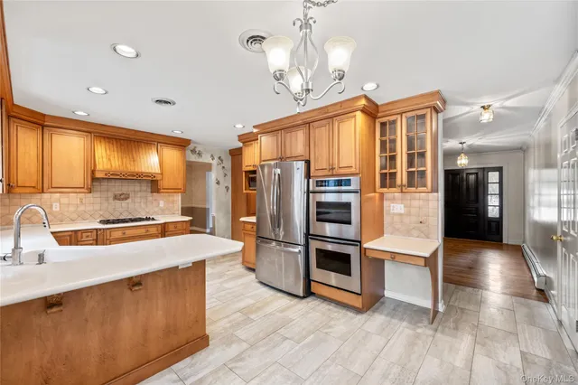 a large kitchen with stainless steel appliances a stove a refrigerator a sink dishwasher with a dining table and chairs with wooden floor