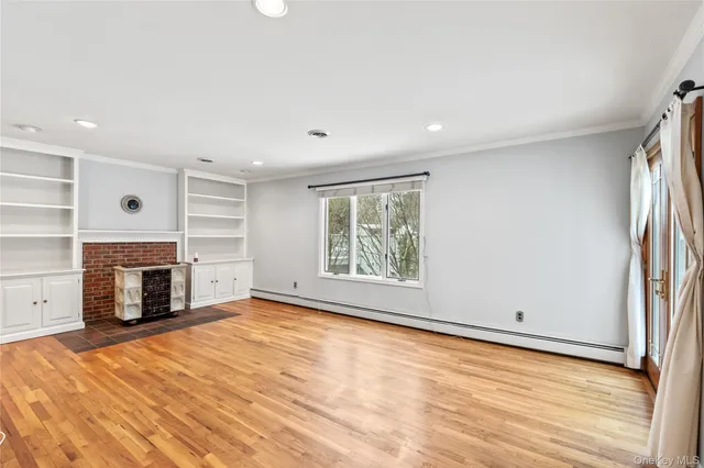 a view of empty room with a fireplace and wooden floor