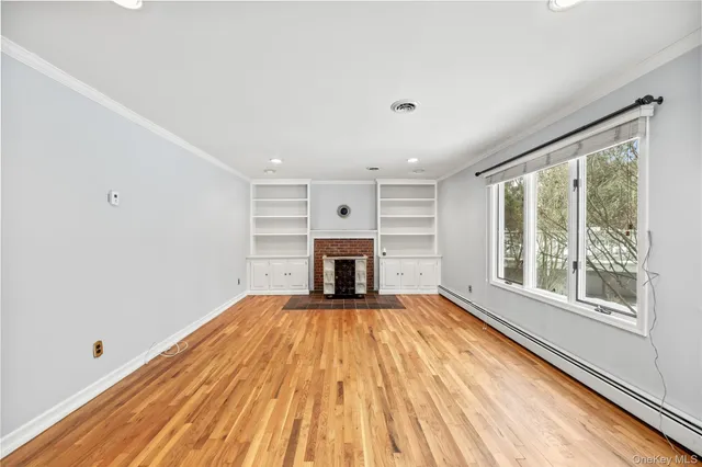 a view of a room with wooden floor fireplace and windows