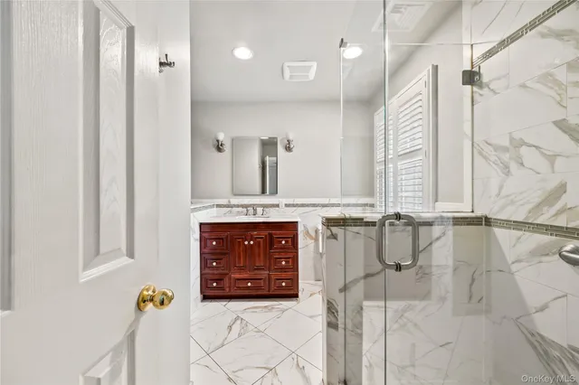 a bathroom with a granite countertop sink a mirror and shower