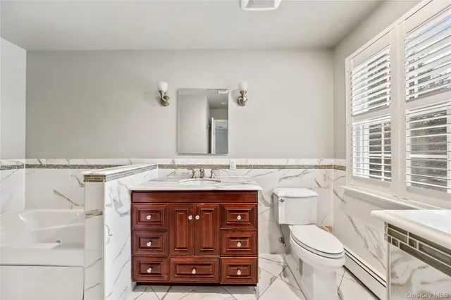 a bathroom with a granite countertop toilet sink and mirror