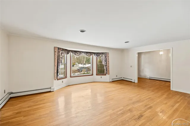 a view of an empty room with a window and a kitchen