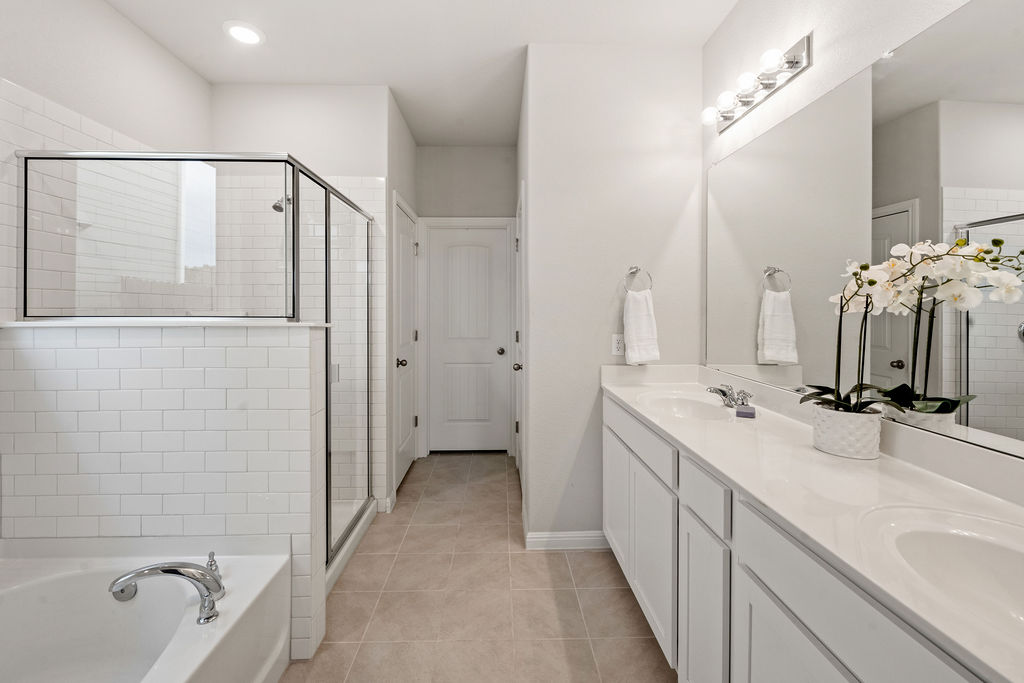 2417 Roosevelt Road Leander, TX 78641 - Photo 16 of 40 Bathroom with double vanity, a garden tub, light tile patterned flooring, and a stall shower
