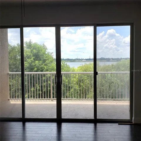 a view of an empty room with wooden floor and windows