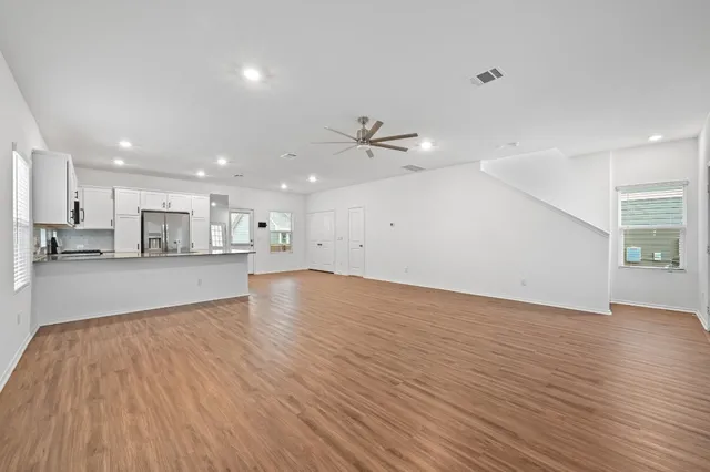 a view of kitchen with kitchen island a sink wooden floor and a refrigerator