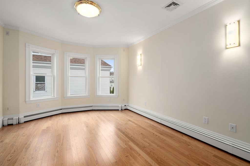 88 Coolidge Street, Unit 2 Brookline, MA 02446 - Photo 8 of 14 an empty room with wooden floor and windows
