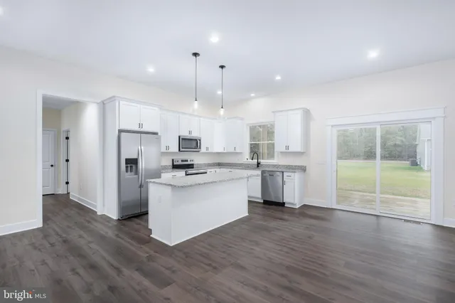 a kitchen with stainless steel appliances granite countertop a sink a stove a refrigerator and white cabinets