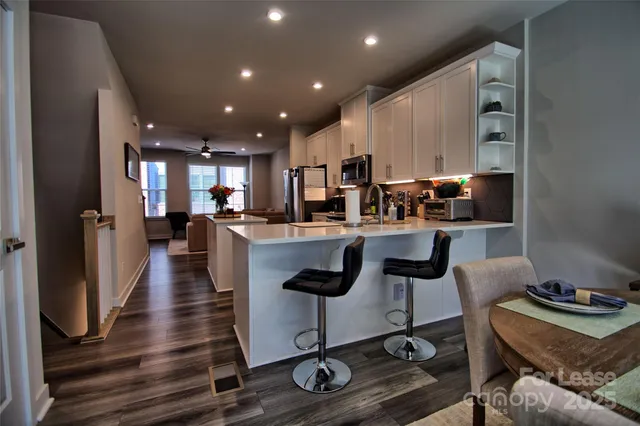 a kitchen with stainless steel appliances kitchen island granite countertop a stove a refrigerator and a dining table with wooden floor