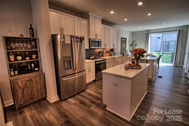 a kitchen with stainless steel appliances a refrigerator a sink wooden floor and cabinets