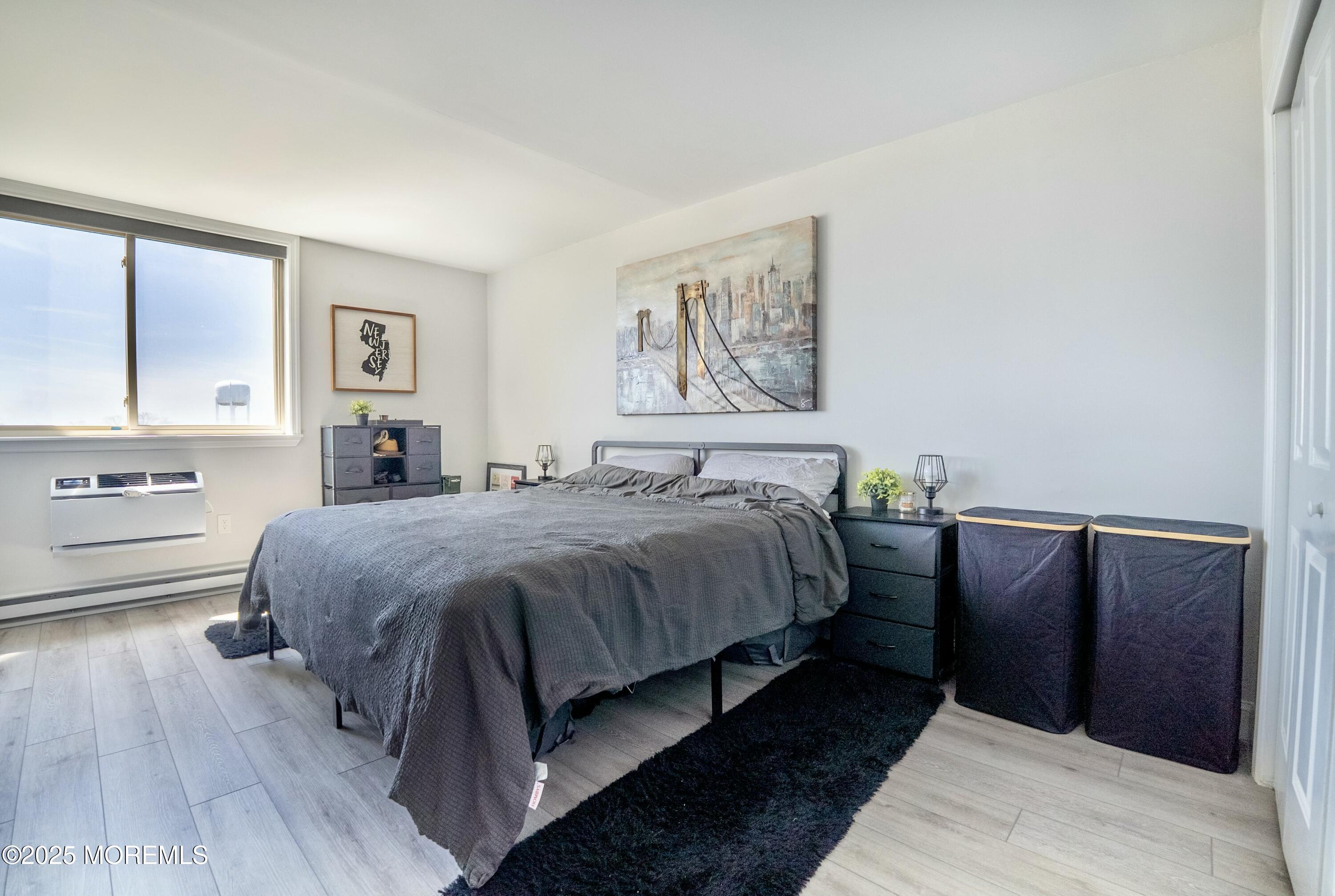 1000 River Road, Unit 6G Belmar, NJ 07719 - Photo 6 of 9 a bedroom with a bed and a painting on the wall