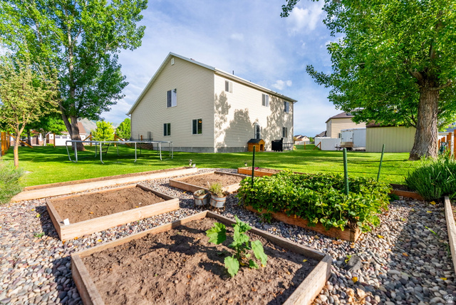 2485 South 1100th Street West Logan, UT 84321 - Photo 38 of 53 Expansive backyard featuring a manicured lawn, established trees, and multiple raised garden beds set within a gravel pathway