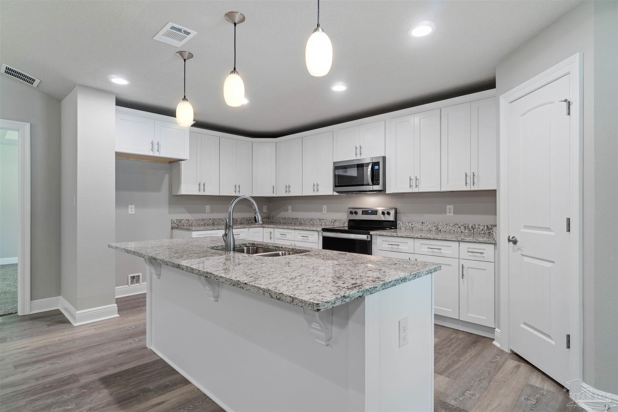 4289 Carl Booker Road Milton, FL 32583 - Photo 17 of 40 a kitchen with kitchen island granite countertop stainless steel appliances a sink a stove a microwave a center island and cabinets