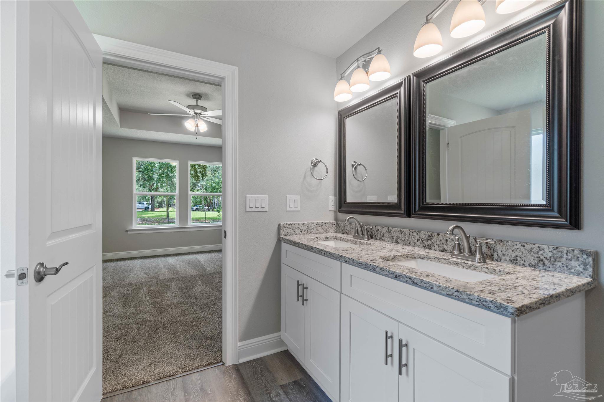 4289 Carl Booker Road Milton, FL 32583 - Photo 26 of 40 a bathroom with a granite countertop sink a large mirror and a vanity